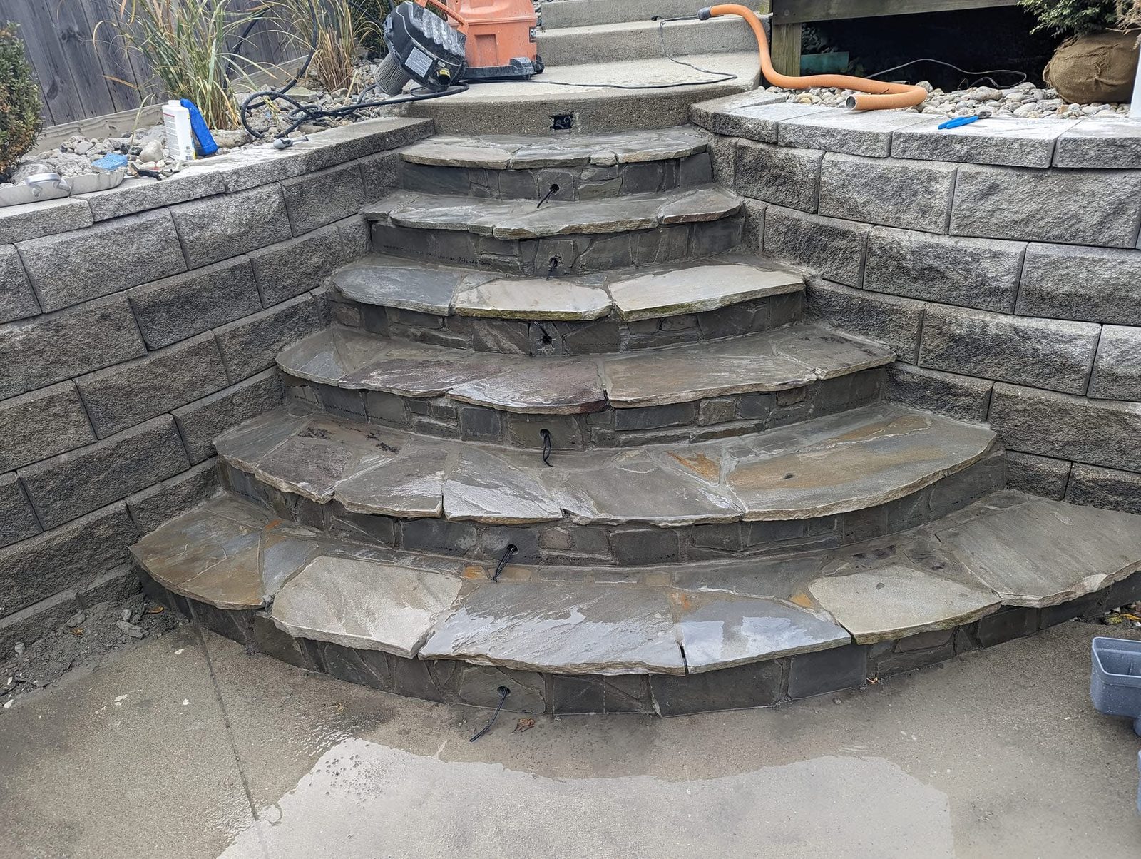 Curved natural flagstone steps between block retaining walls