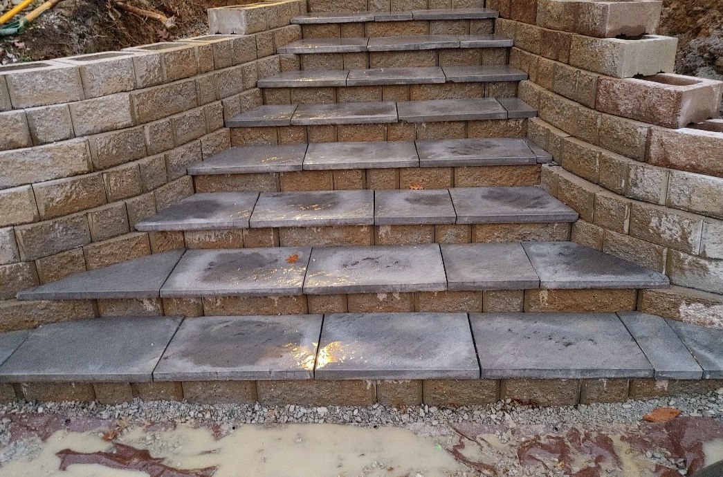Block retaining wall with integrated stone steps